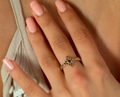 Black diamond yellow gold ring on finger